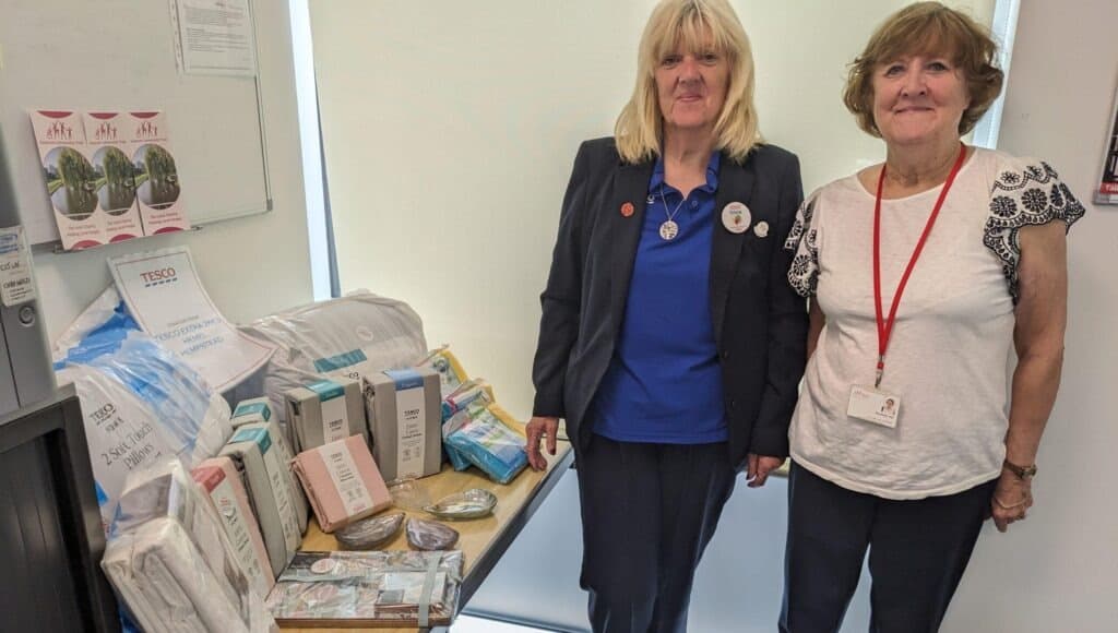 A picture of Tricia Glenister from Tesco, Jarman Park, and Rosemary Hall of Dacorum Community Trust receiving bedding items donated by Tesco