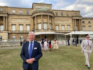 A photo of our trustee, Mike Edis, standing in front of Buckingham Palace.