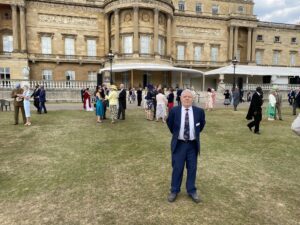 A photo of our trustee, Tony Williams, standing in front of Buckingham Palace.